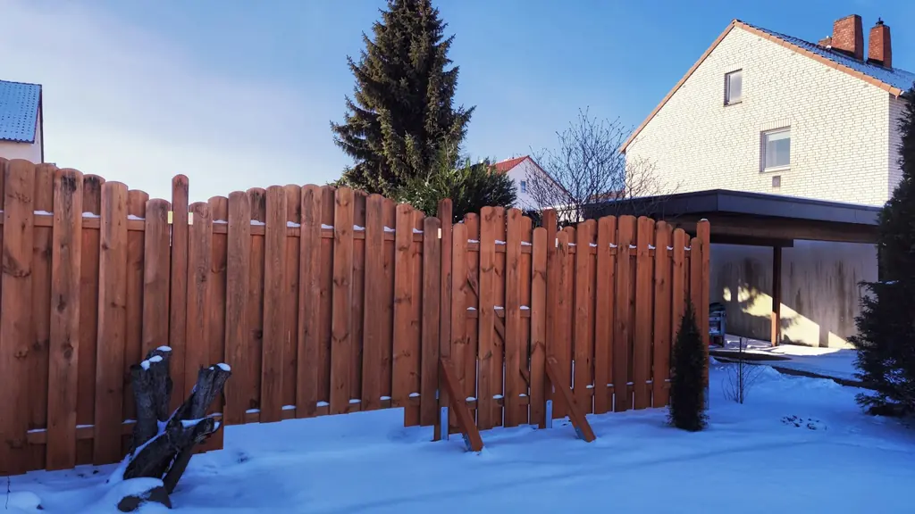 A wood fence beside a house in winter
