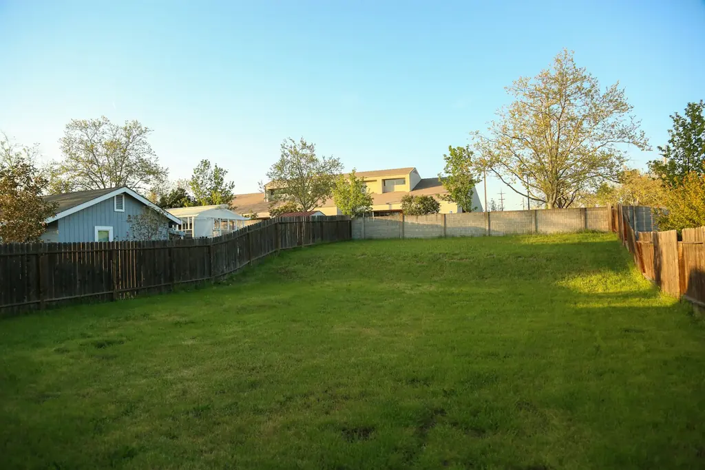 A backyard lawn lined by a fence